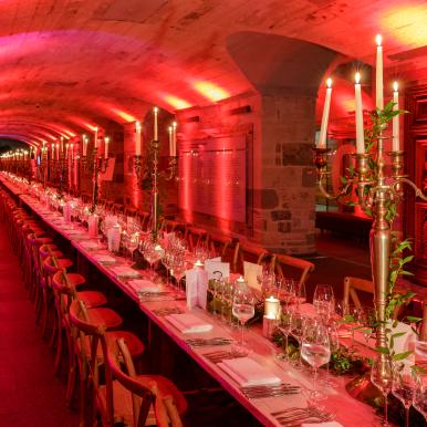 Elegant dinner party table set up at National Museum of Scotland in red lighting 