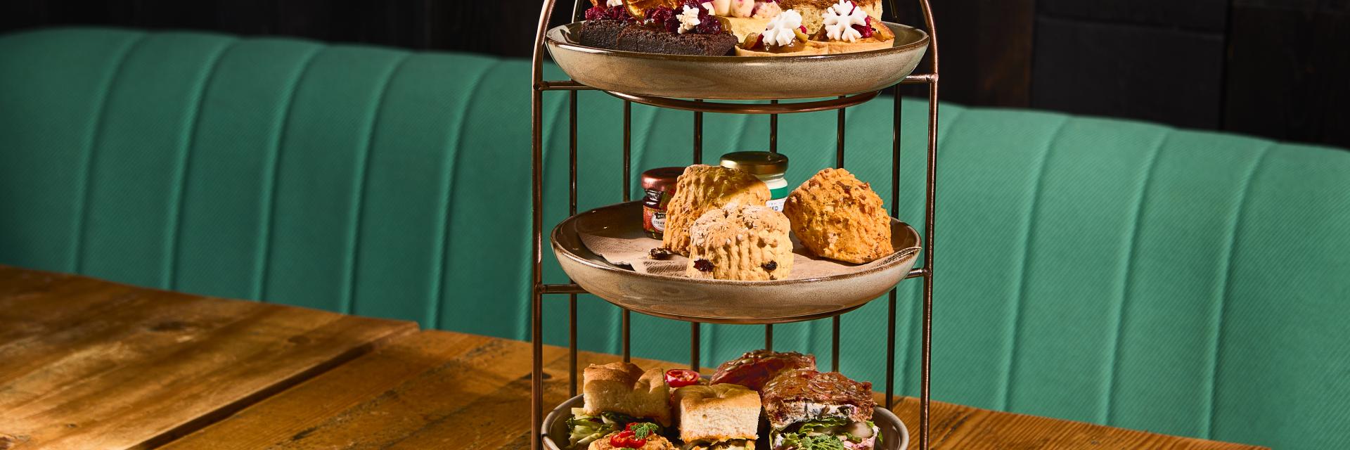 Three-tiered Afternoon Tea stand with home-baked cakes, mini scones, and savouries pastries. 
