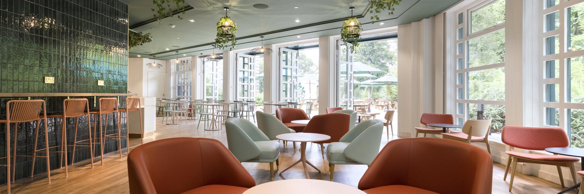Green patterned sofa and colourful comfy chairs around a small round table at the Terrace Cafe. 